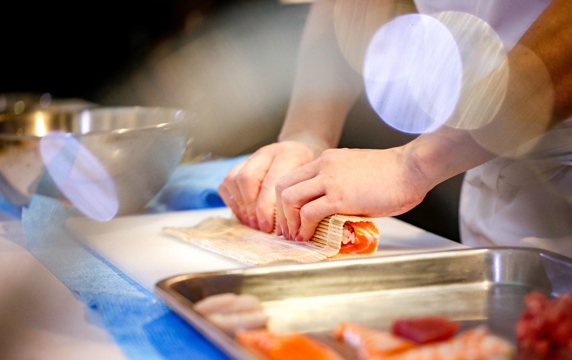 Chef making sushi, Sushi roll making preparation, close up on chef hands, Salmon sushi